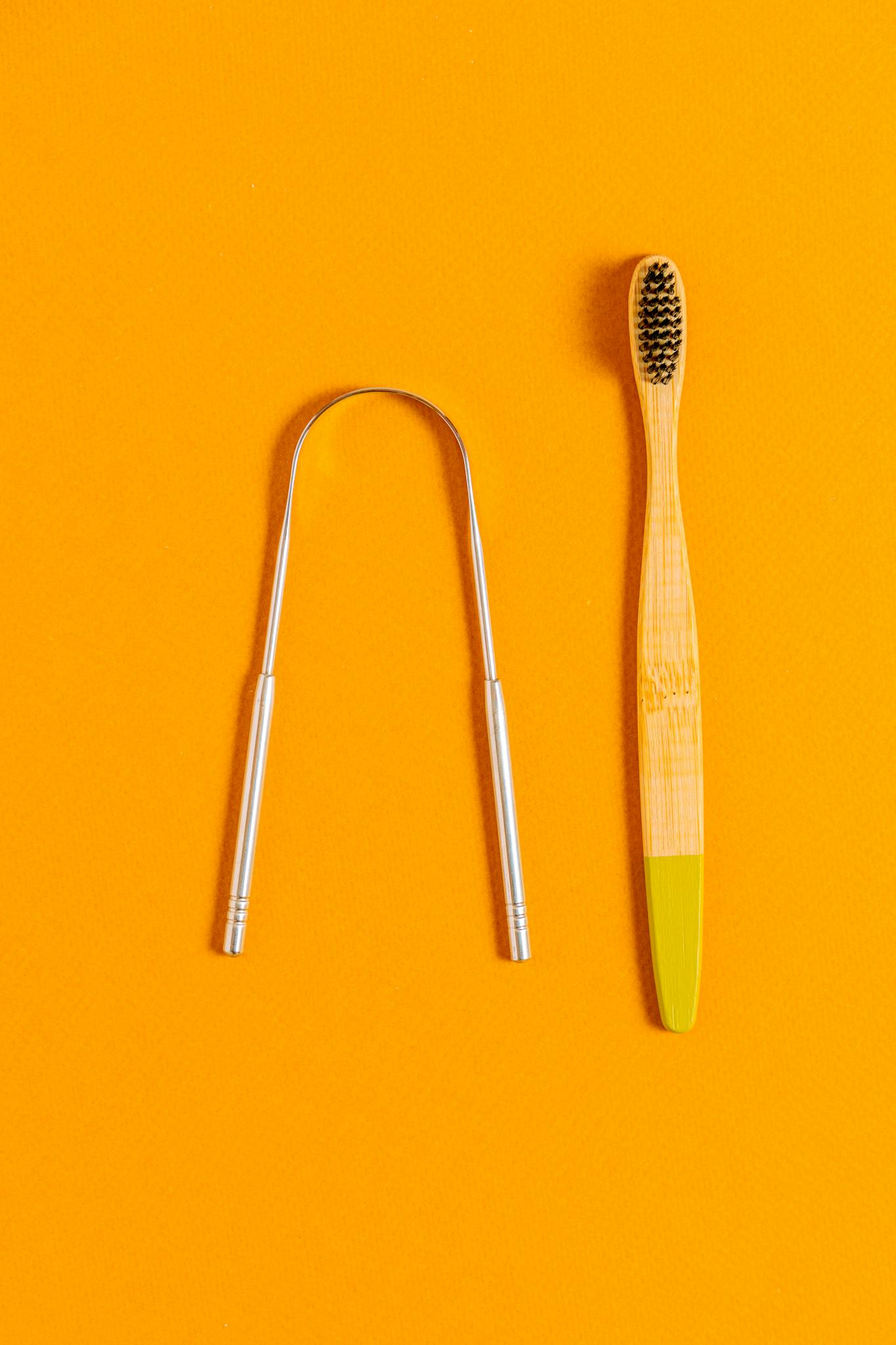 A Bamboo Toothbrush And Tongue Scraper On