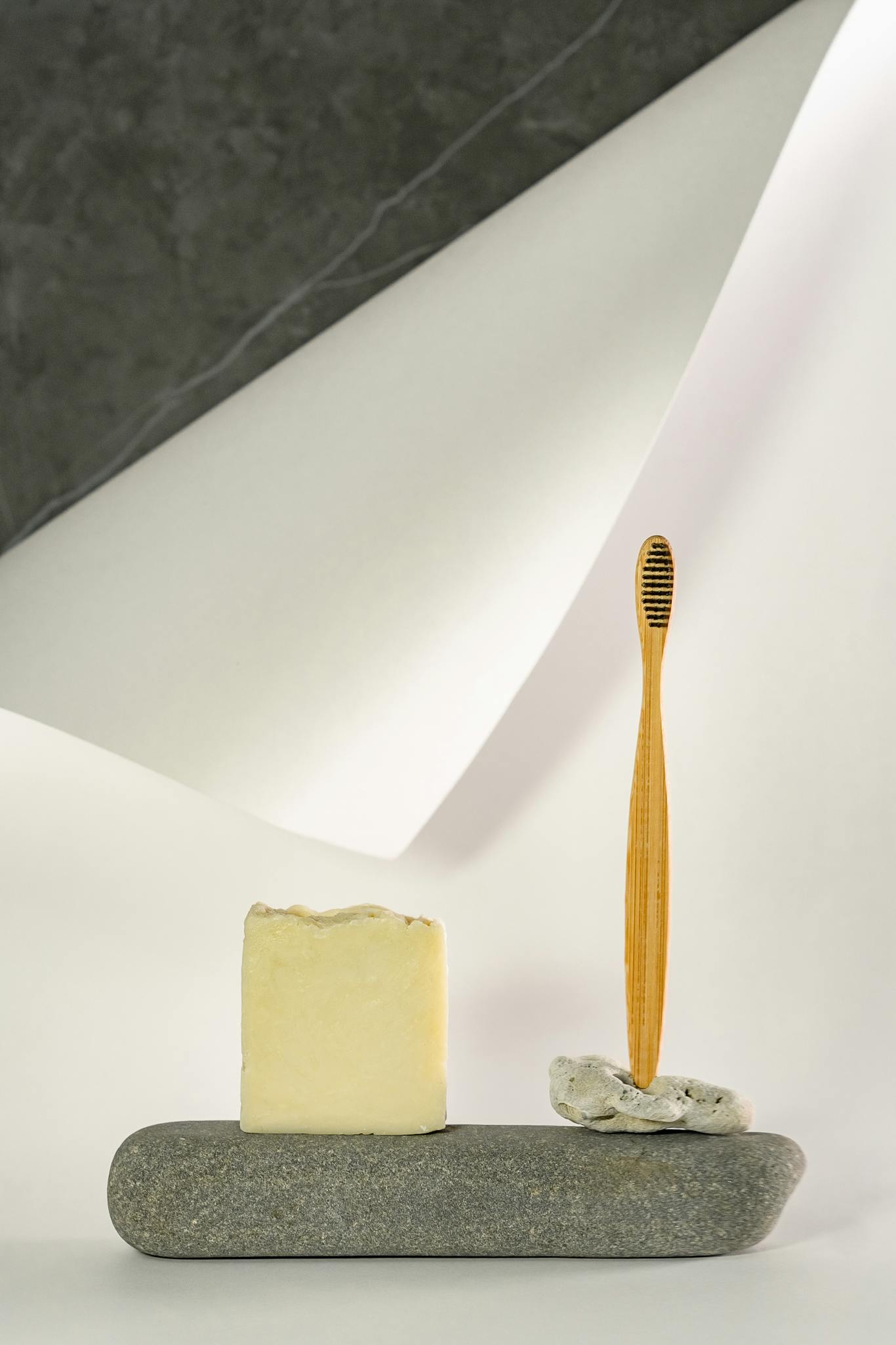 A stylish display of soap and bamboo toothbrush on a stone in modern design.