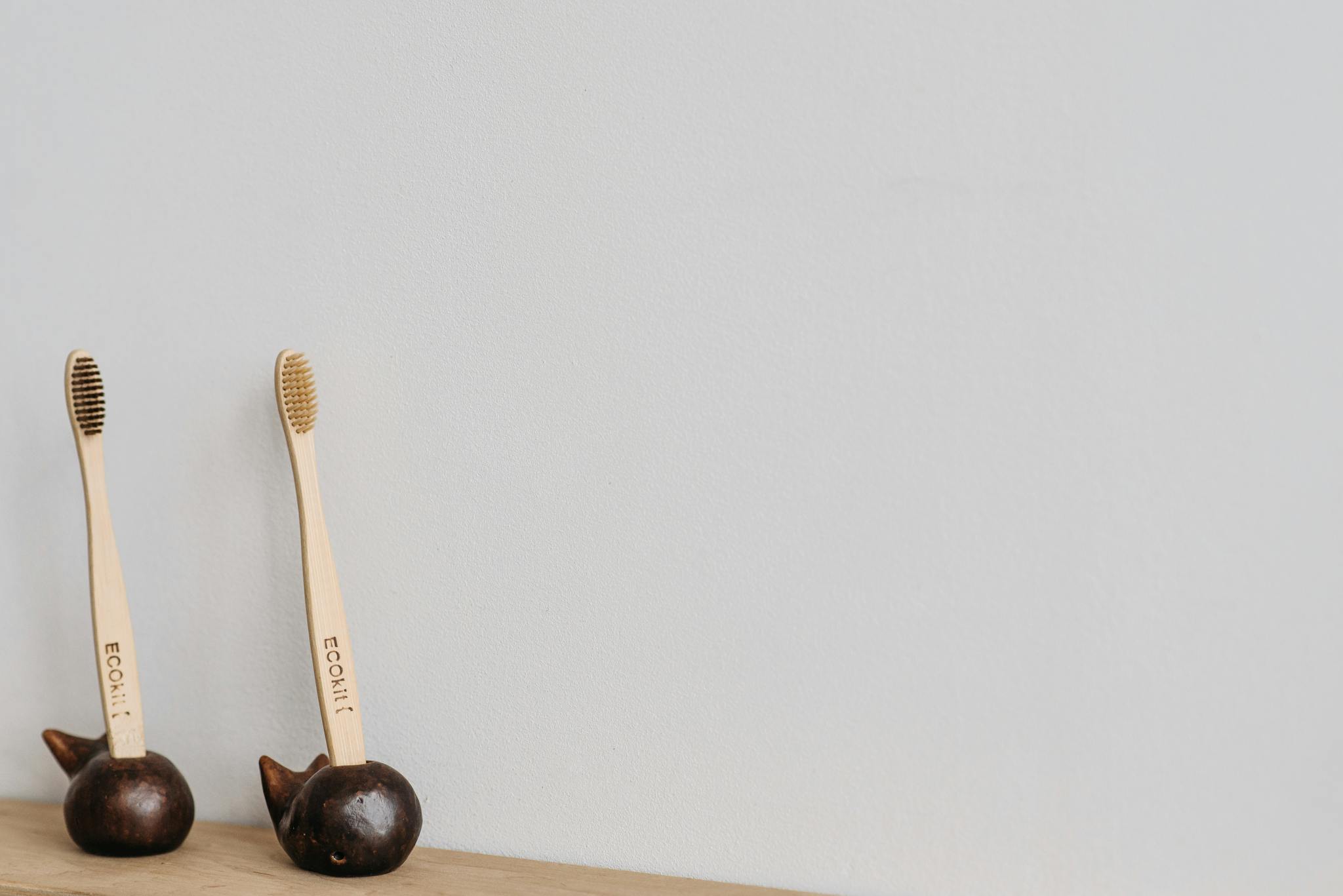 Services Pair of eco-friendly wooden toothbrushes in unique holders on a white background, ideal for promoting sustainable oral hygiene.
